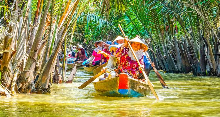 Mensen die boten peddelen door weelderige tropische kanalen.