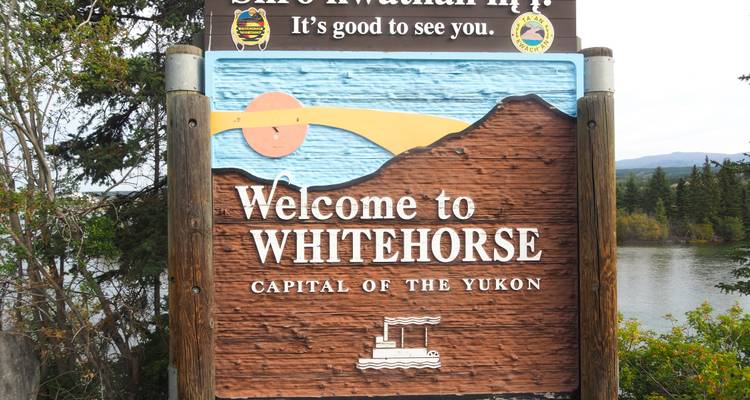 Panneau de bienvenue pour Whitehorse avec le fleuve Yukon en arrière-plan.