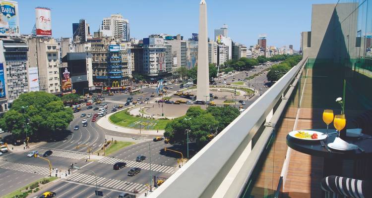 Vue de l'Obélisque de Buenos Aires depuis un balcon avec une table de petit-déjeuner.