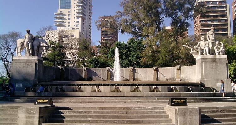 Elegant fountain surrounded by sculptures in a city park.