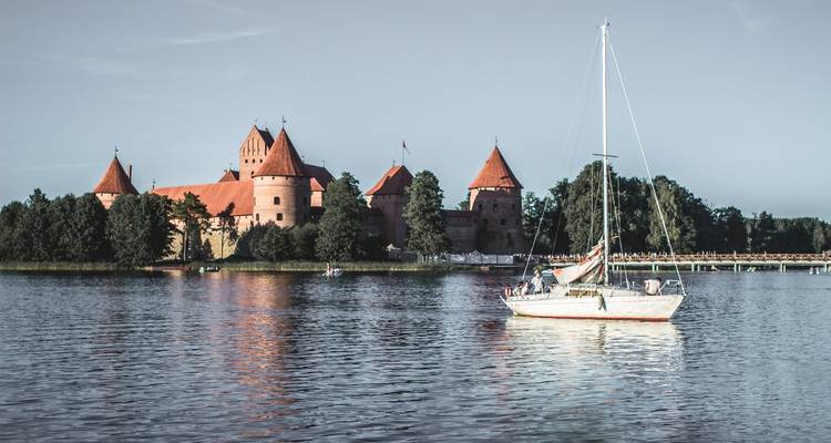 Trakai Eilandkasteel gezien vanaf de overkant van een meer met een zeilboot.