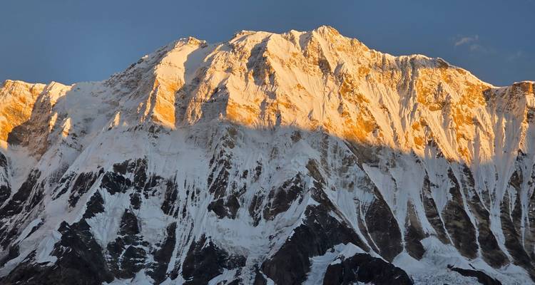 Met zon verlichte sneeuwbedekte wand van Annapurna I die gloeit tijdens het gouden uur