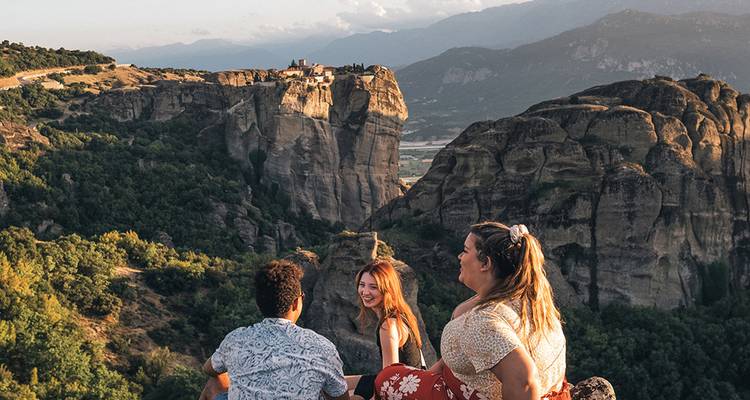 Los amigos ríen juntos mientras contemplan los dramáticos monasterios de arenisca de Meteora.