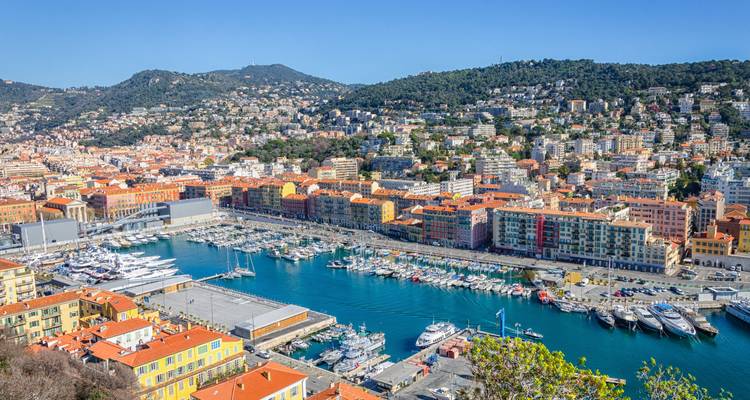 Vue panoramique d'un port de plaisance dans une ville côtière entourée de collines.