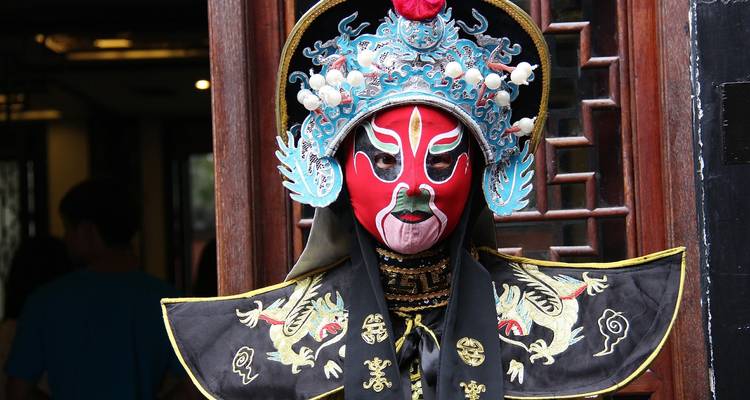 Persona con traje de ópera china tradicional y una máscara facial pintada.
