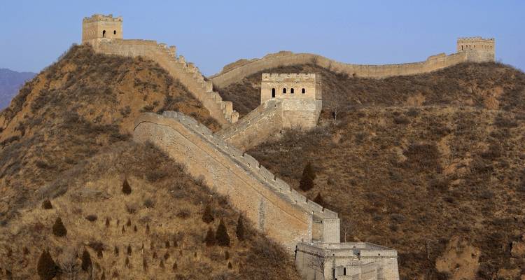 Gran Muralla China extendiéndose a través de las colinas bajo un cielo despejado.