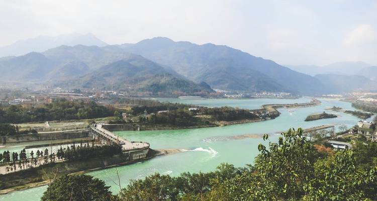 Una vista amplia de un río serpenteando a través de un valle exuberante bajo un cielo nublado.