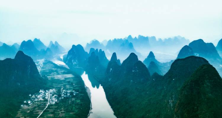 Vista aérea brumosa de los dramáticos picos de piedra caliza flanqueando el sinuoso río Li cerca de Guilin