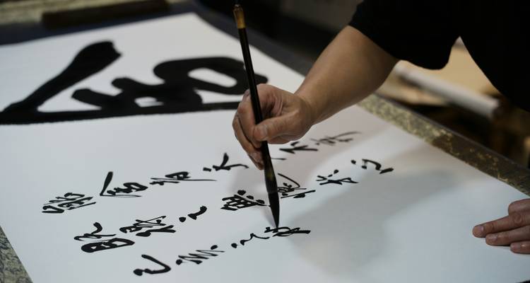 Un artista practica caligrafía china tradicional con un pincel de tinta en papel blanco