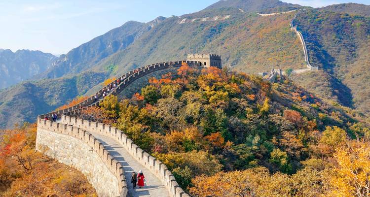 Sección de la Gran Muralla extendida sobre colinas otoñales llenas de color bajo cielos azules