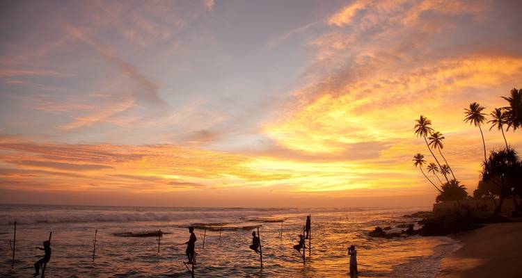 Pêcheurs en silhouette au coucher du soleil sur la plage.