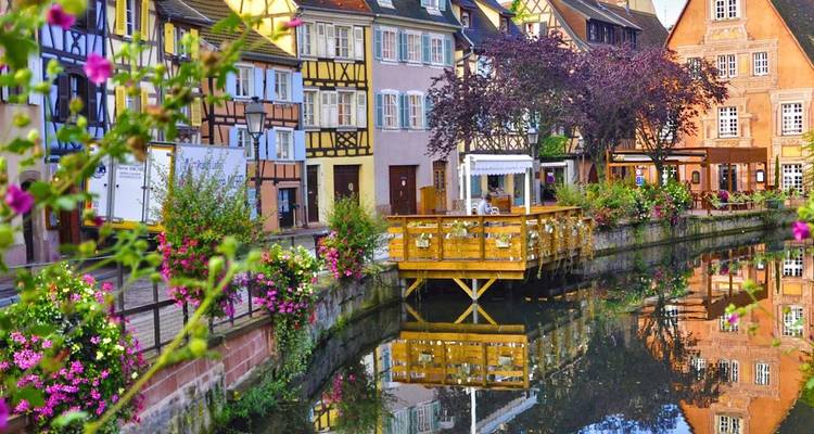 Picturesque canal lined with colourful timber-framed houses and overflowing flower boxes in Colmar.