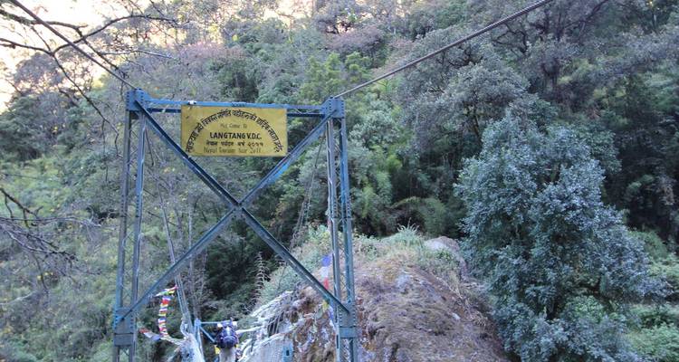 Metalen brug met een bord waarop Langtang Valley staat.