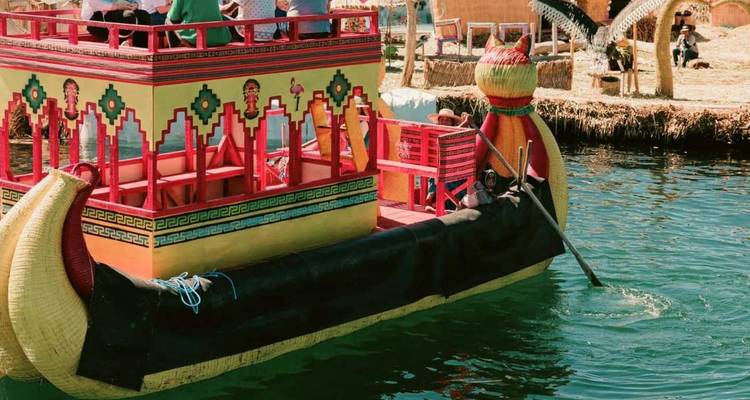 Felgekleurde rietboot met decoratieve patronen drijft op smaragdgroen meerwater.
