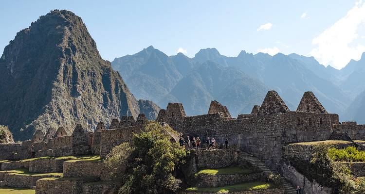 Panoramablick auf Machu Picchus Steinruinen vor dramatischen zerklüfteten Gipfeln unter klarem Himmel.