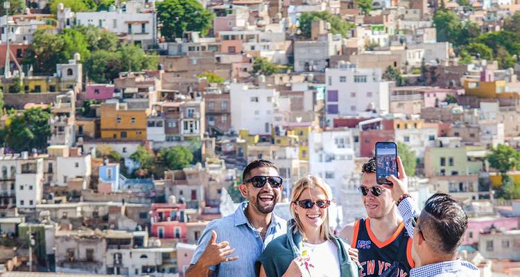 Gruppe macht ein Selfie vor der Kulisse der bunten Hügelhäuser der Stadt Guanajuato.