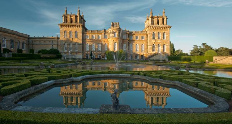 Stattlicher Palast und formelle Gärten mit Spiegelung in einem Teich.