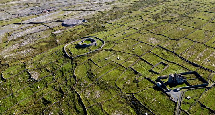 Vue aérienne de Dún Aonghasa avec des murs de pierre et des champs verts.