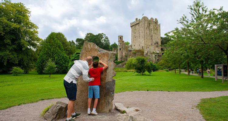 Château de Blarney avec de la verdure et un père et son fils au premier plan.