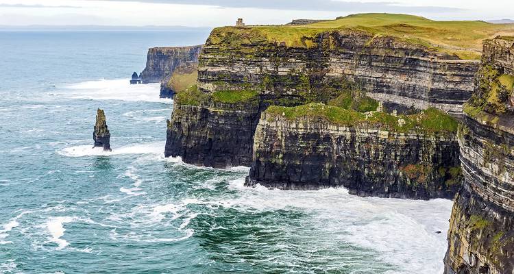 Falaises de Moher surplombant l'océan avec des vagues qui se brisent contre les rochers.