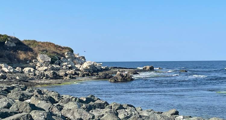 Côte rocheuse de la mer Noire avec un ressac doux et un ciel bleu clair par une journée ensoleillée.