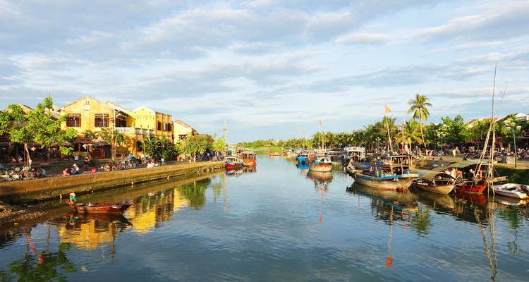 Malerische Aussicht auf Hoi An mit Booten auf einem Fluss und bunten Gebäuden.