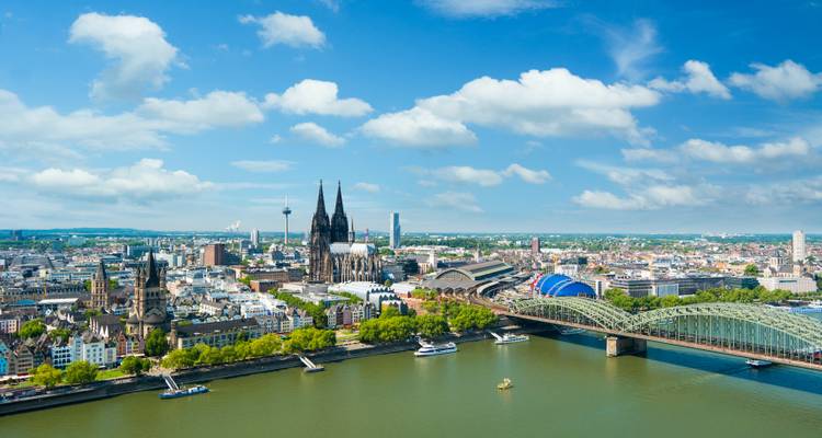 Panorama aéreo despejado de Colonia con la catedral, el puente Hohenzollern y el Rin fluyendo por debajo.