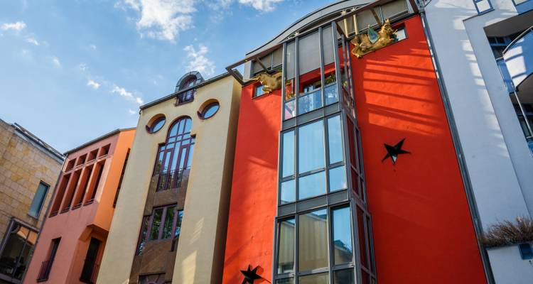 Bold modern building with bright orange and yellow facades and decorative stars against a blue sky.