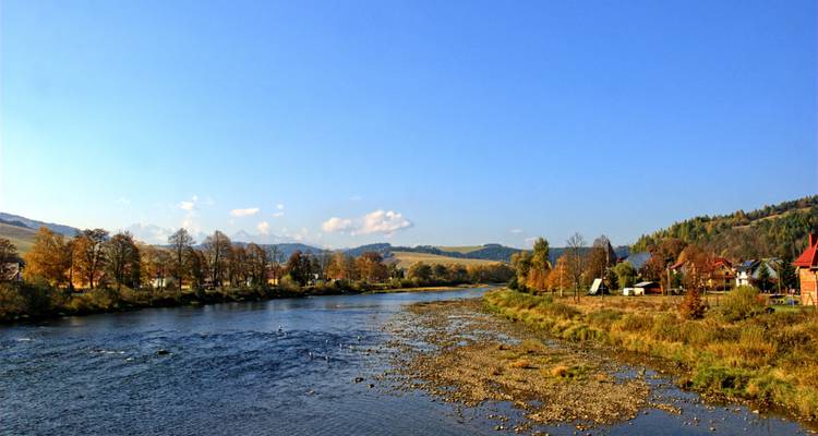 A scenic river with trees and hills in the backdrop.
