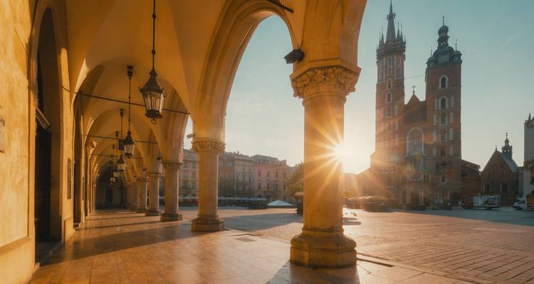 Sunset shining through archways with historic buildings.