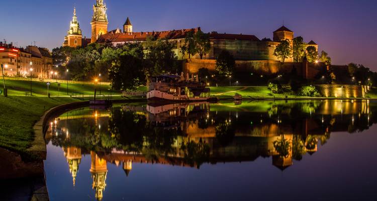 Krakau's historische gebouwen verlicht in de nacht met reflecties.