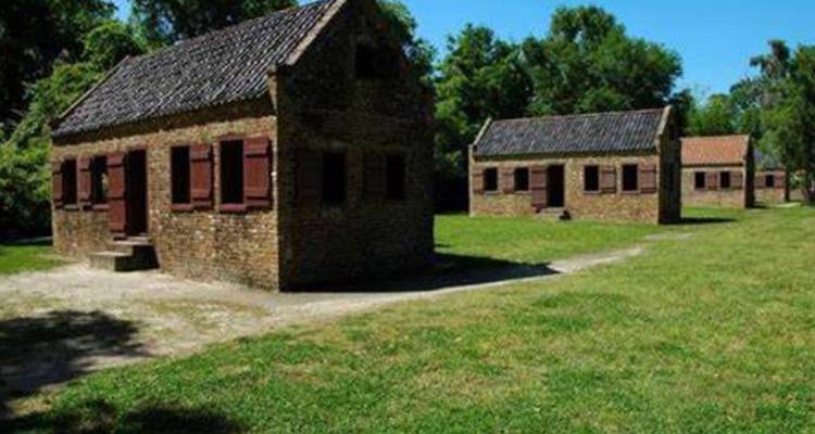 Rangée de maisons historiques en brique dans un espace ouvert herbeux.