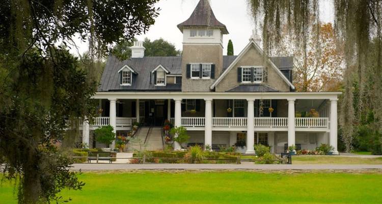 Manoir historique du sud avec un grand porche et un jardin.