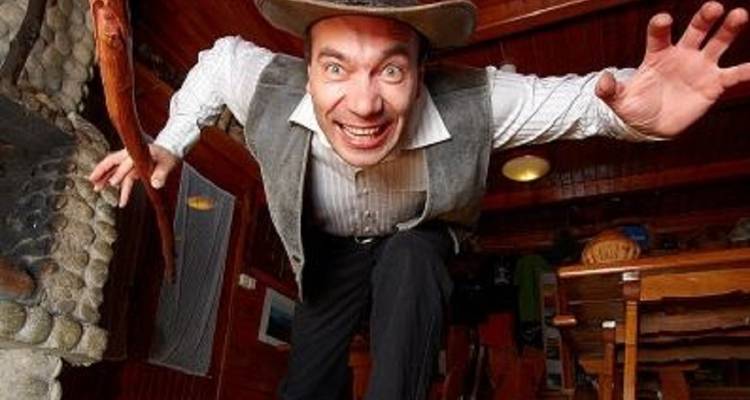 Mann im Kostüm, der enthusiastisch in rustikaler Umgebung posiert.