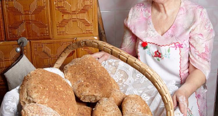 Ältere Frau hält einen Korb mit Brot.