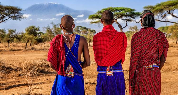 Trois personnes en tenue traditionnelle masaï regardent vers le mont Kilimandjaro.