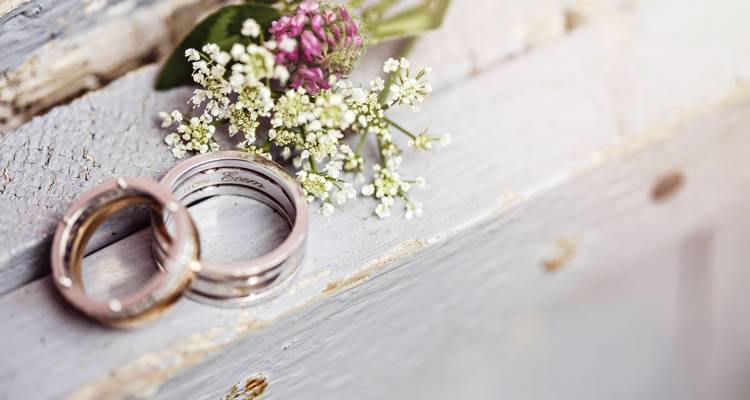 Gros plan de fleur et d'alliances sur une surface en bois.