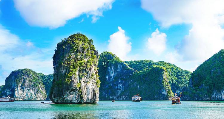 Schilderachtig uitzicht op kalkstenen eilanden en boten onder een heldere blauwe hemel.