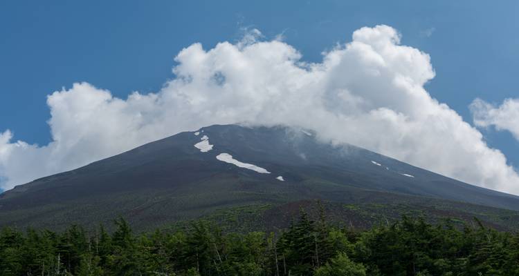 Una vista de un pico de montaña con nubes sobre él.
