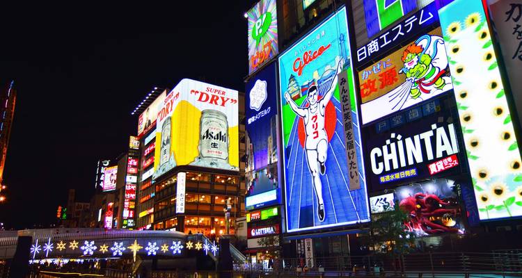 Vista nocturna de Dotonbori en Osaka con el famoso letrero del hombre corriendo de Glico y anuncios brillantemente iluminados.