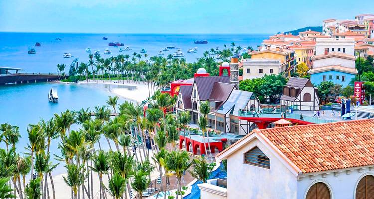Küstenstadt mit bunten Gebäuden und Palmen am Meer.