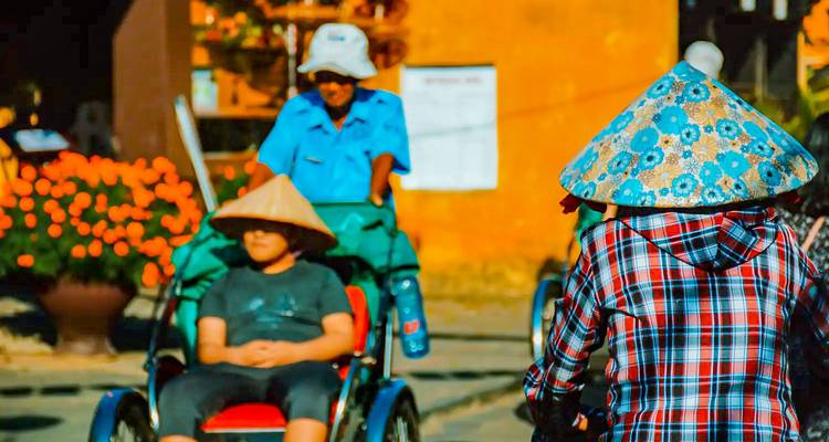 Menschen, die eine Fahrt mit traditionellen vietnamesischen Zyklos genießen und Kegelhüte tragen.