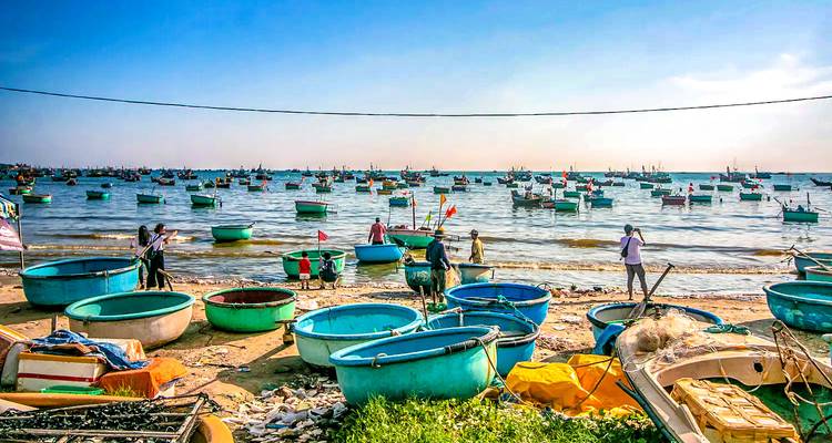 Drukke strand met kleurrijke ronde boten en mensen aan de kust.