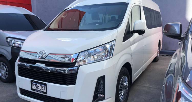 Camionnette blanche garée parmi d'autres véhicules dans un parking.