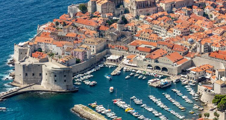 Vue aérienne élevée de la vieille ville de Dubrovnik et de la marina entourées de murs médiévaux sur la mer Adriatique turquoise.