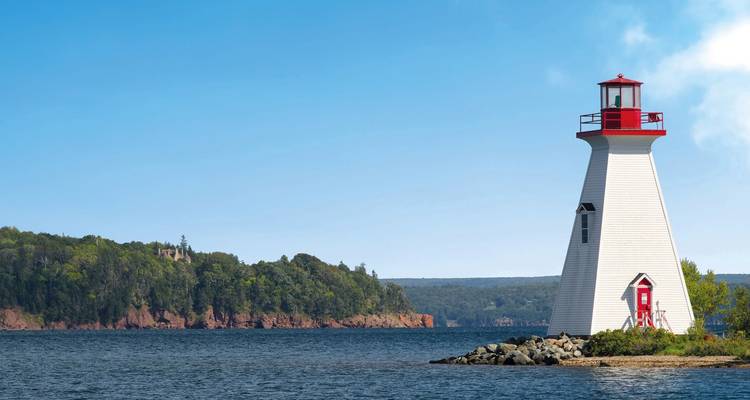 Faro blanco y rojo cerca de una costa.