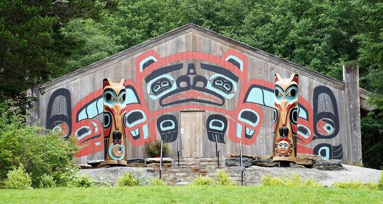 Traditional building with colorful totem poles in front.