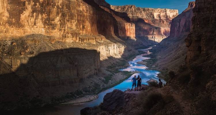 Mensen die op een klif staan en uitkijken over een rivier in een canyon.