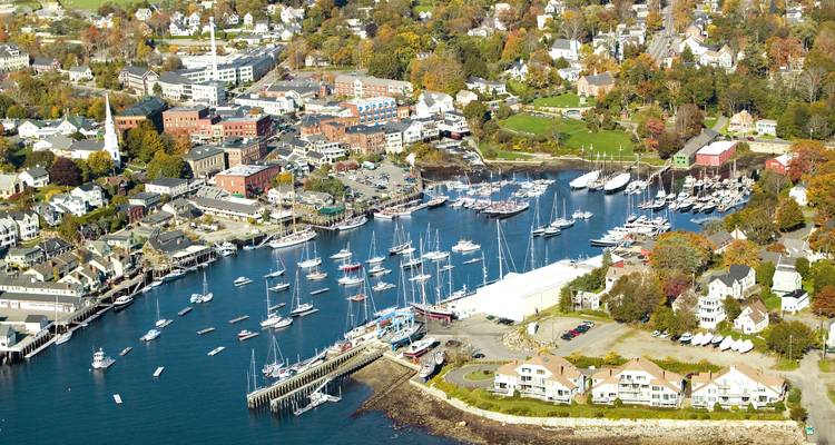 Aerial panorama of a New England coastal town with marina, sailboats and colorful autumn trees.