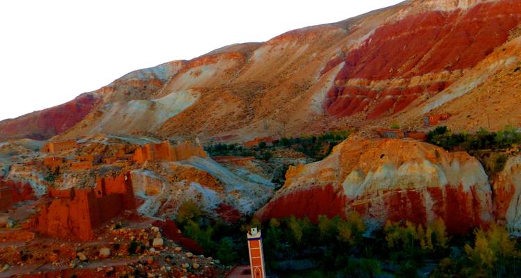Bunte geschichtete Felshügel mit einem kleinen Wüstendorf.